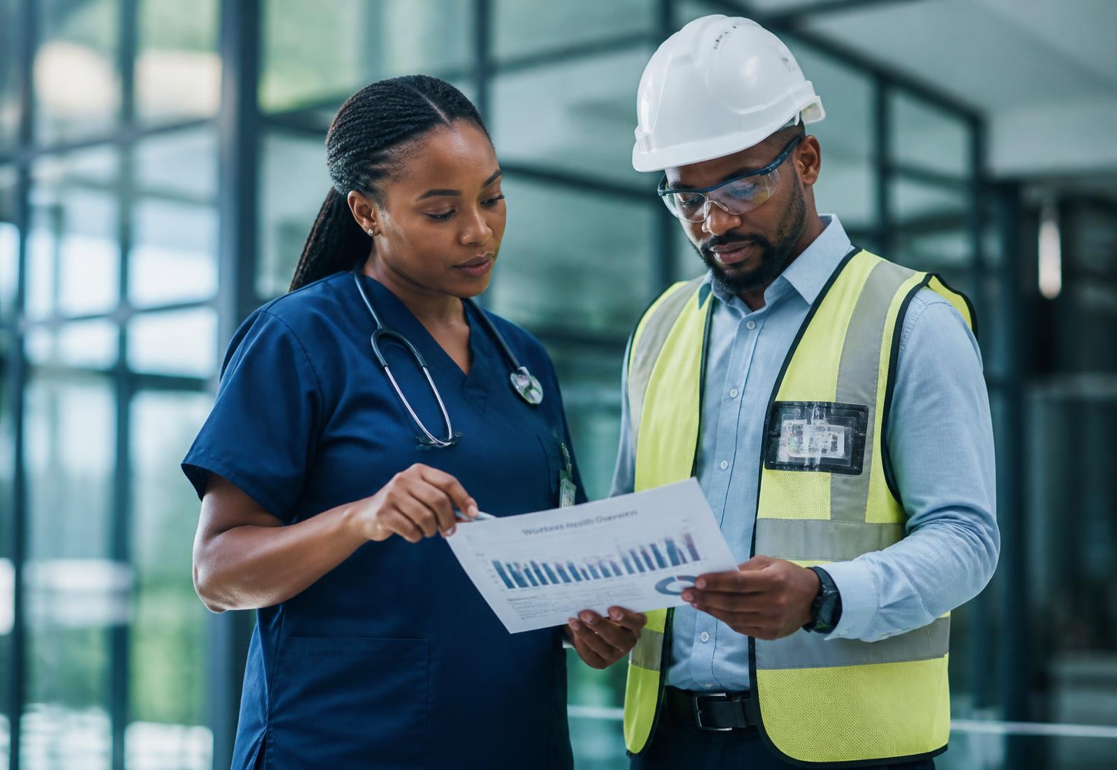 Occupational health physician reviewing a workforce health report with an industrial site engineer